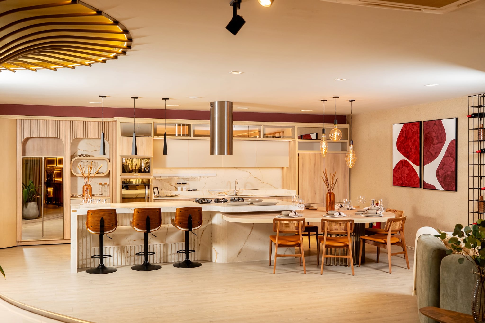 Cocina integrada con isla de mármol, banquetas y una mesa de comedor con sillas de madera y asiento naranja